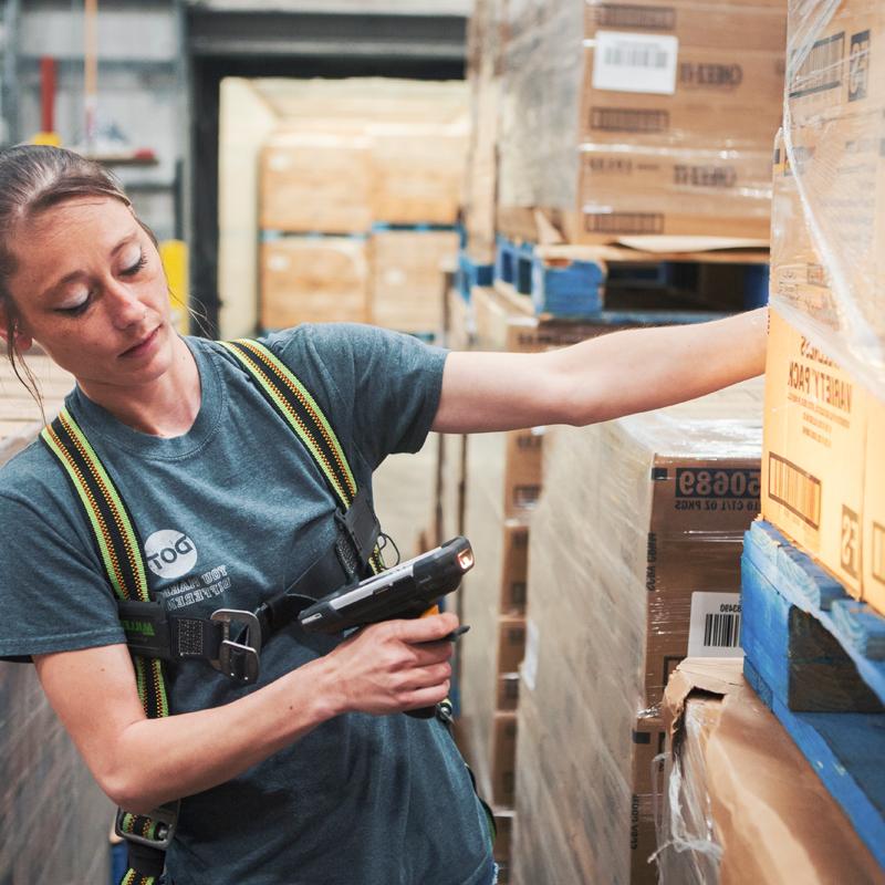 girl using a scanner to scan boxes at a warehouse